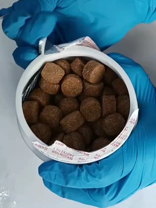 Echtes Foto: die frisch geöffnete Dose voller runder, gesprenkelter Chews, die Folie halb abgezogen